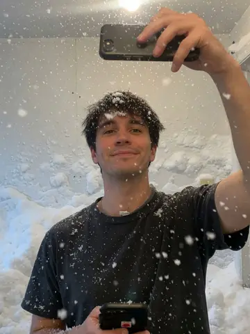 Exempel på Snöstorm inomhus: Tung snö faller inne i rummet, med tjocka drivor på golvet och möblerna och snöflingor i personens hår.