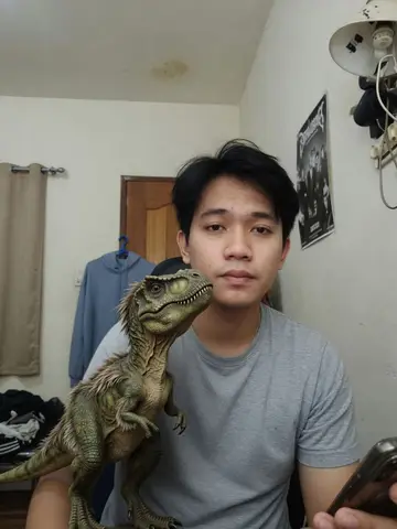 Exempel på Dino som husdjur: Personen har en realistisk T-rex-unge som når ungefär till knät bredvid sig, och dinon tittar nyfiket upp.