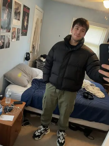 Exempel på Streetwear-fit: Personen bär en oversized streetwear-outfit med pösig dunjacka, cargobyxor och klumpiga sneakers, utan logotyper.