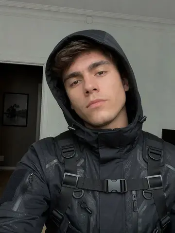 Exempel på Techwear: Personen bär svart futuristisk techwear med huvjacka, remmar och spännen, med ansiktet synligt.